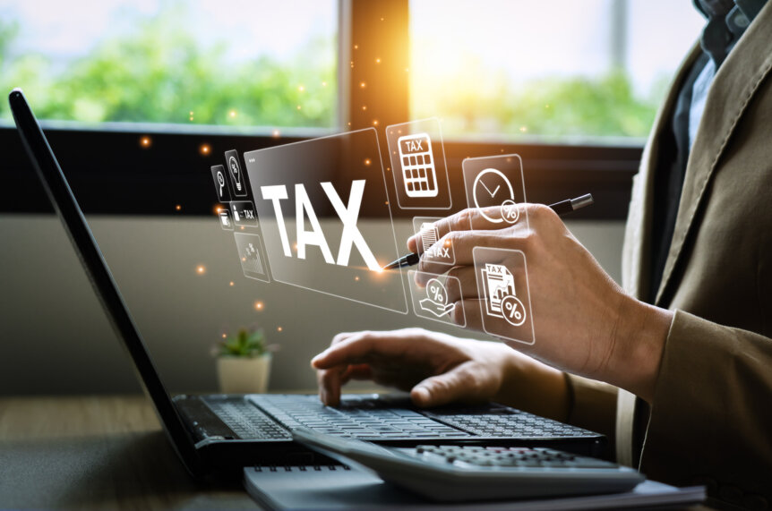 Person working on a laptop with floating digital tax icons, representing financial and tax considerations involved in inheriting a home.
