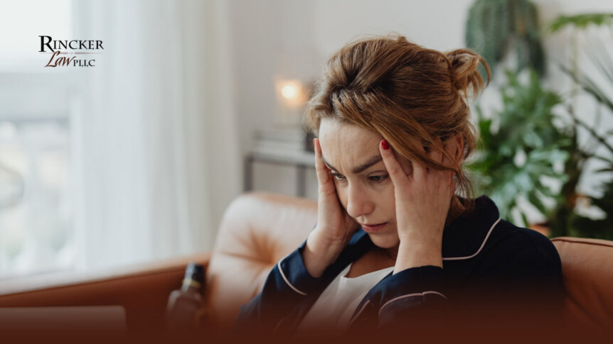 Person sitting on a sofa with their head in their hands, expressing stress in a home setting.